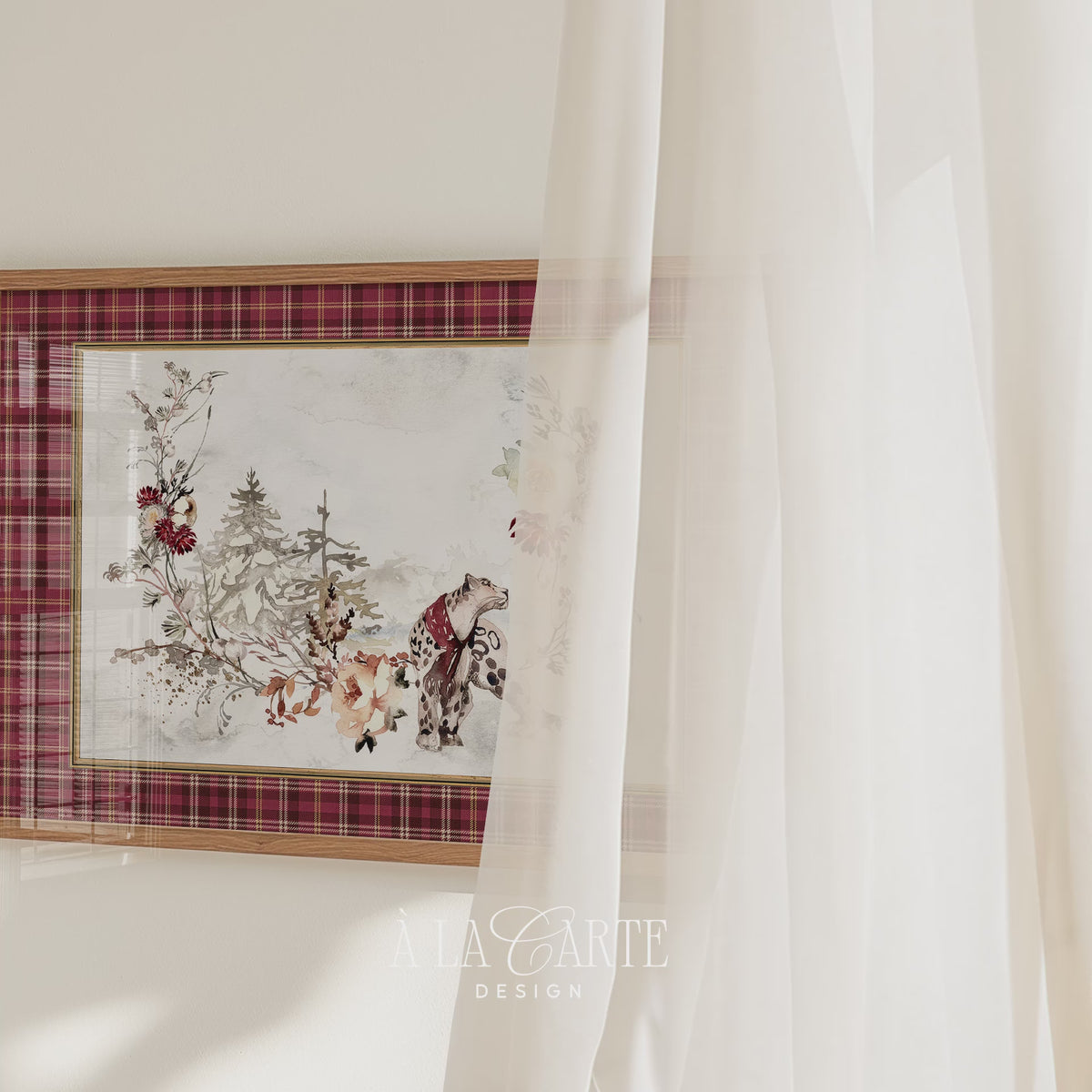 Printable Christmas wall art featuring a watercolor snow leopard in a red scarf, surrounded by snowy evergreen trees, winter flowers and branches, framed by a red tartan plaid border.